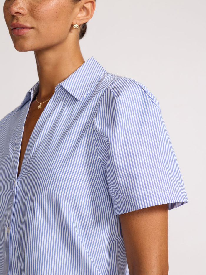 Close-up of a woman wearing an open-collar blue and white pinstripe button-front shirt