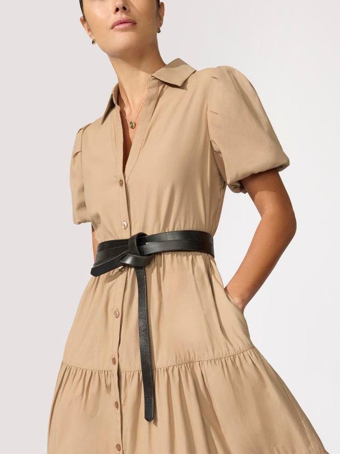 Black leather wrap belt knotted at the waist over a tan button-down shirt dress.