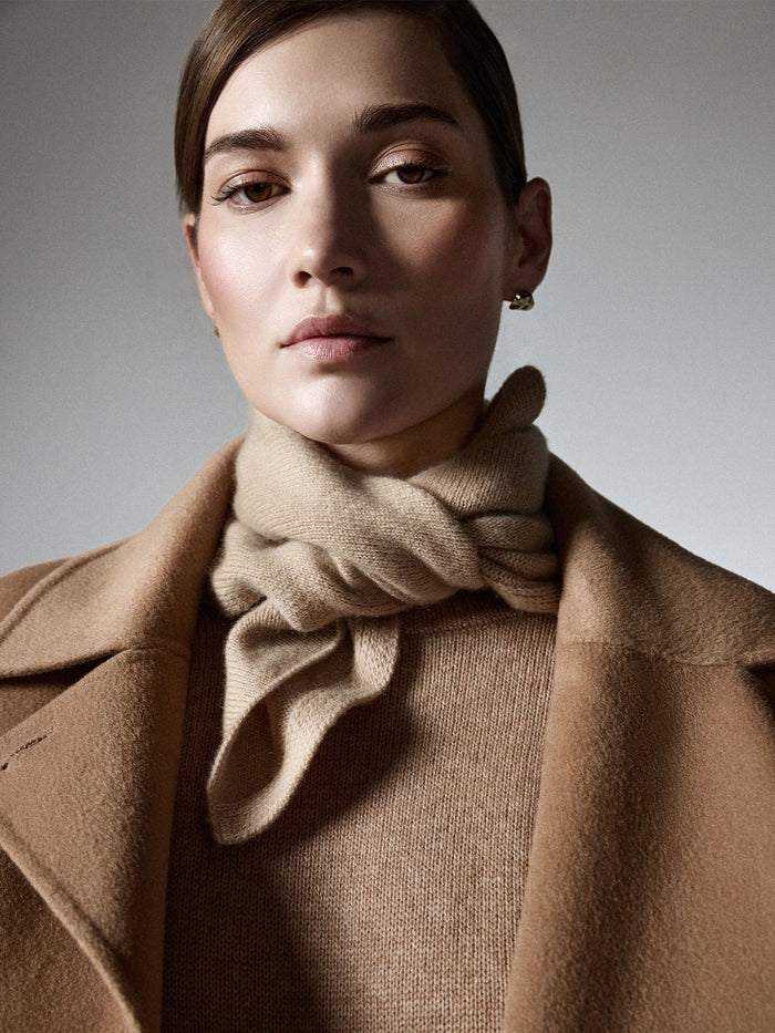 Model wearing the camel cashmere neck square knotted over a matching sweater and coat.