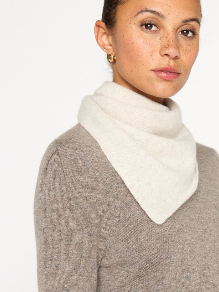 Ivory cashmere neck square draped over a taupe sweater, worn bandana-style at the neckline.