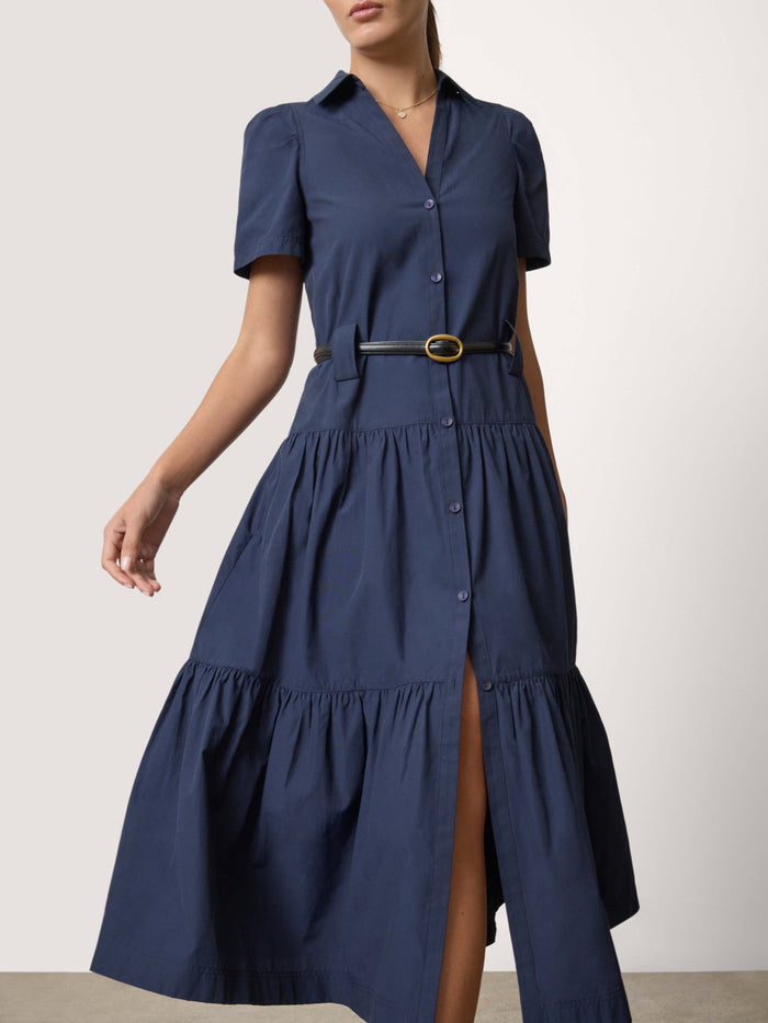 Woman wearing a navy blue tiered maxi shirtdress with a belted waist and front slit