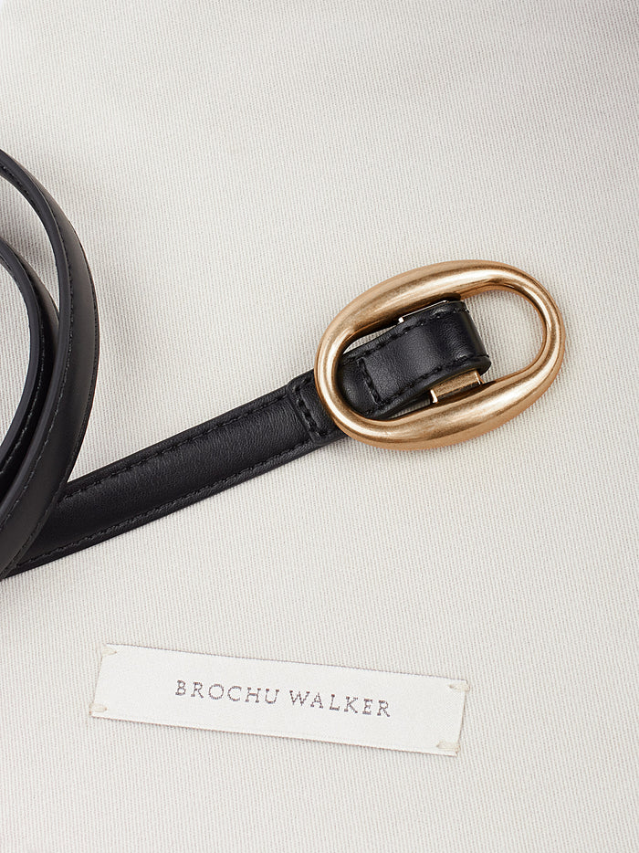 Black leather belt with a gold oval buckle displayed flat with a brand label tag
