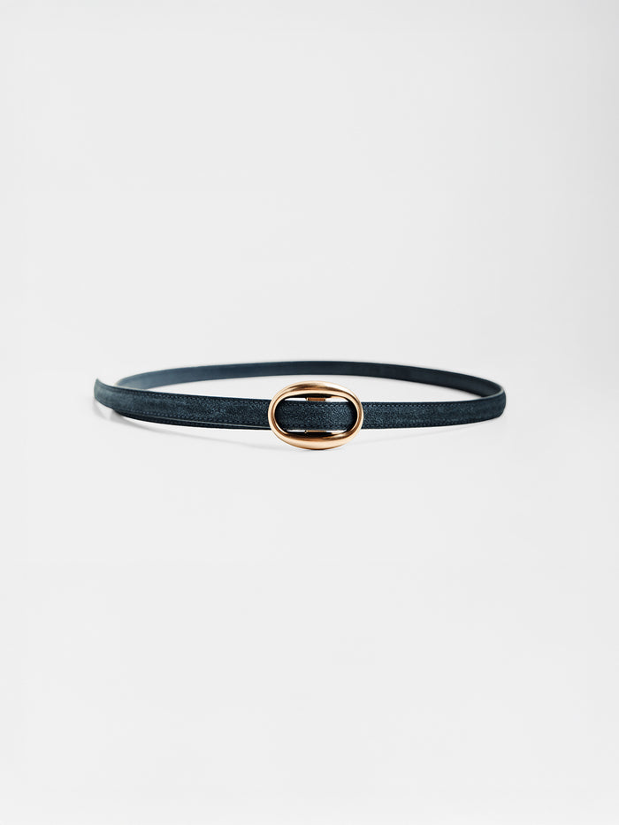 Close-up of a slim navy suede belt with an oval gold buckle