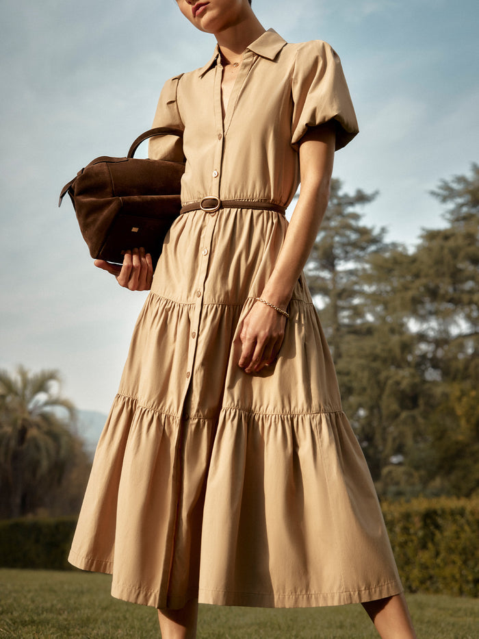 Woman wearing a tan Havana tiered shirtdress with a brown leather belt, carrying a suede bag