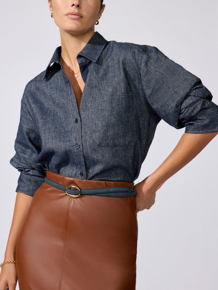 Denim shirt in indigo, tucked into a brown faux-leather skirt with a matching belt, close-up waist detail