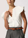 Woman wearing an ivory flutter-sleeve Darya top with a brown leather belt over charcoal Maris shorts