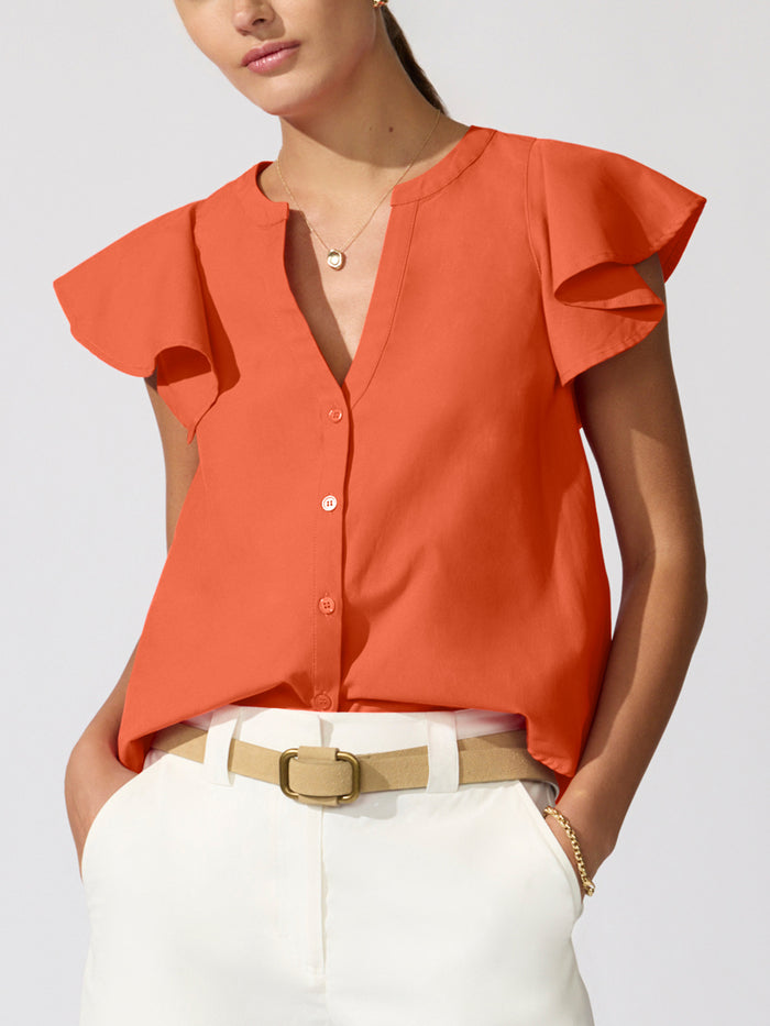Woman wearing an orange flutter-sleeve Darya top with white pants and a tan belt