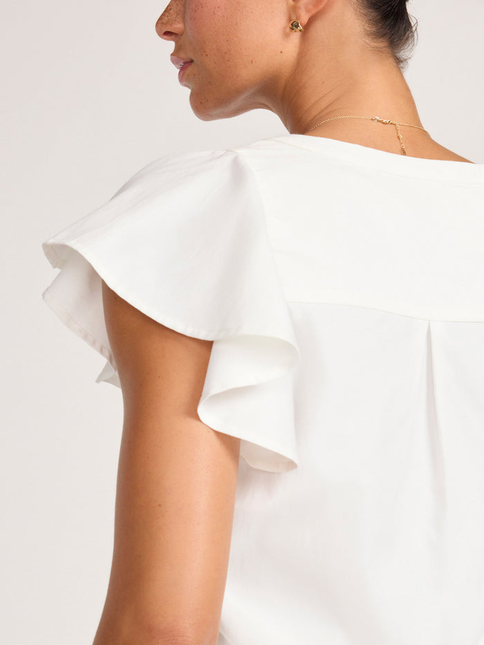 Close-up of the ruffled flutter sleeve on a white V-neck blouse