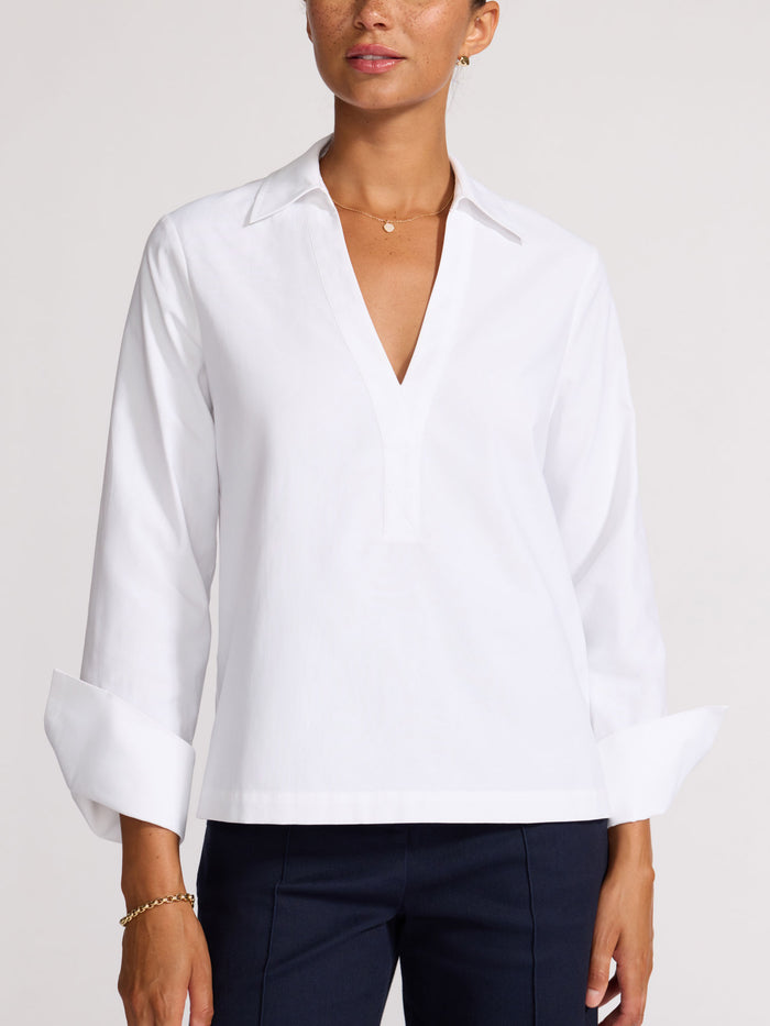 Woman wearing a white V-neck popover shirt with navy trousers
