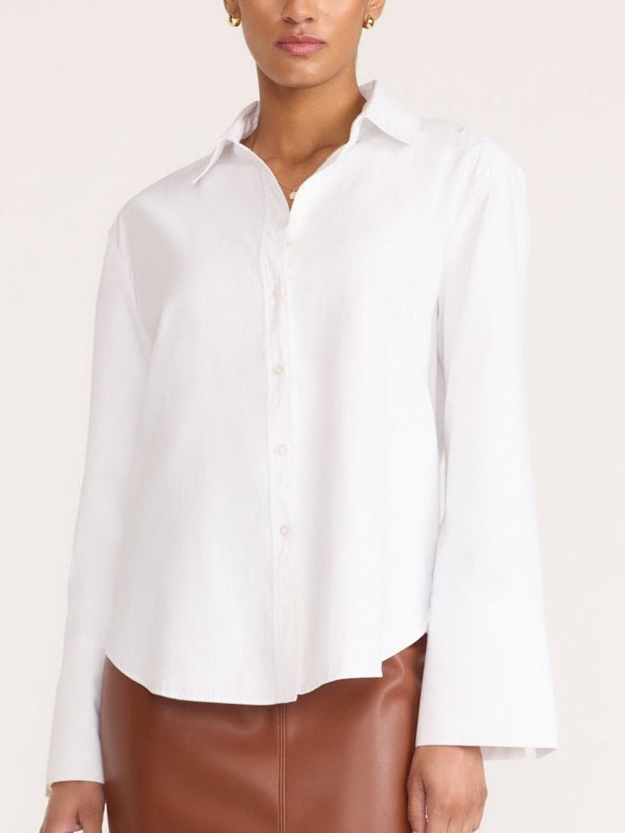 Eliana shirt in salt white, a relaxed-fit button-up blouse paired with brown faux-leather bottoms.