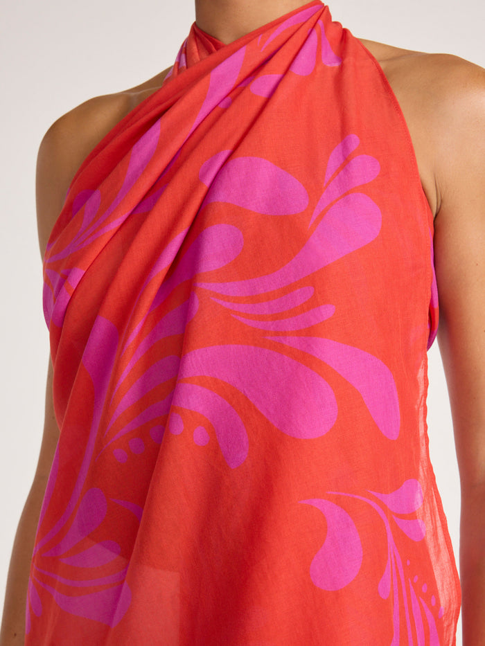 Close-up detail of the orange and pink tropical-print pareo wrap fabric, showing its lightweight gauze texture.