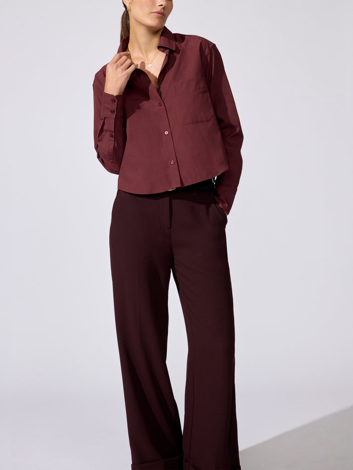Woman wearing a burgundy cropped button-up shirt with matching wide-leg trousers