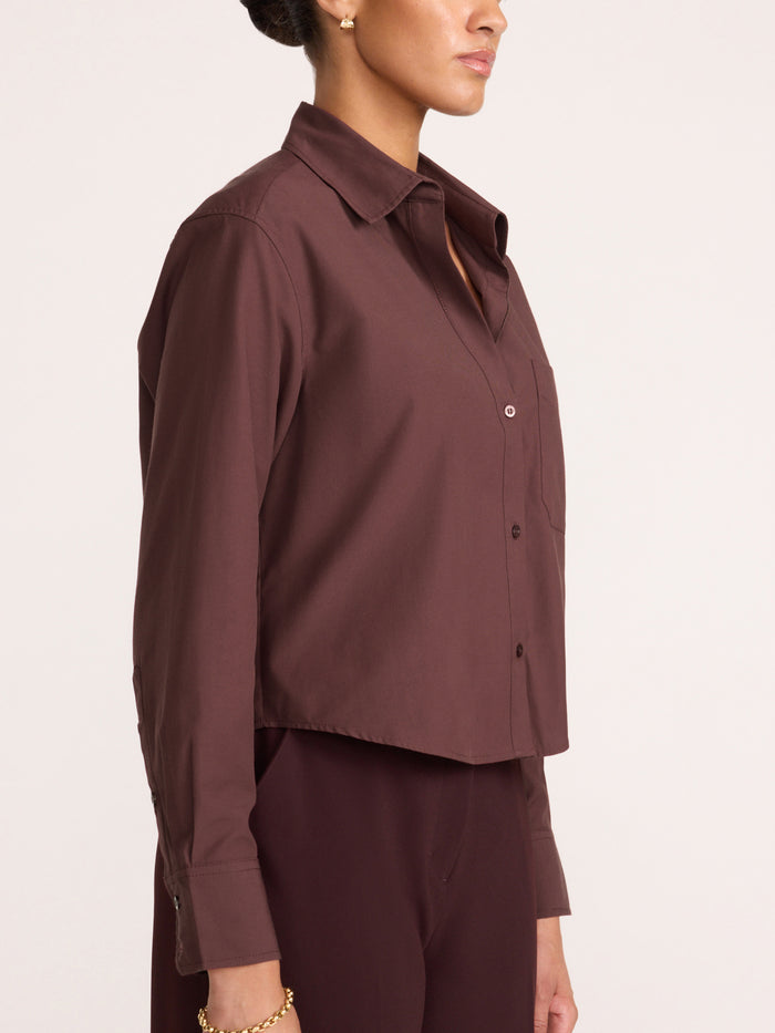 Side profile of a women's cropped button-up shirt in deep plum-brown, styled with matching trousers