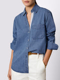 Close-up of a denim button-down shirt with a chest pocket paired with cream trousers