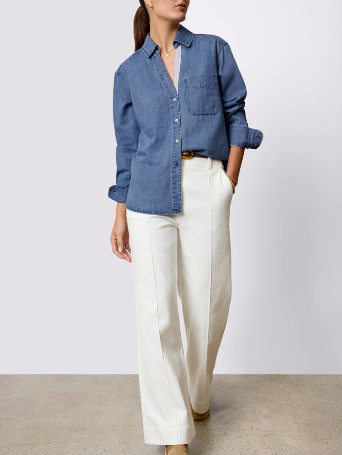 Woman wearing a denim button-down shirt with wide-leg cream trousers