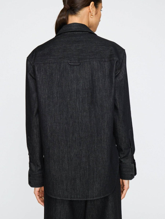 Oversized denim shirt for women with long sleeves, rounded hem, and relaxed fit in dark wash.