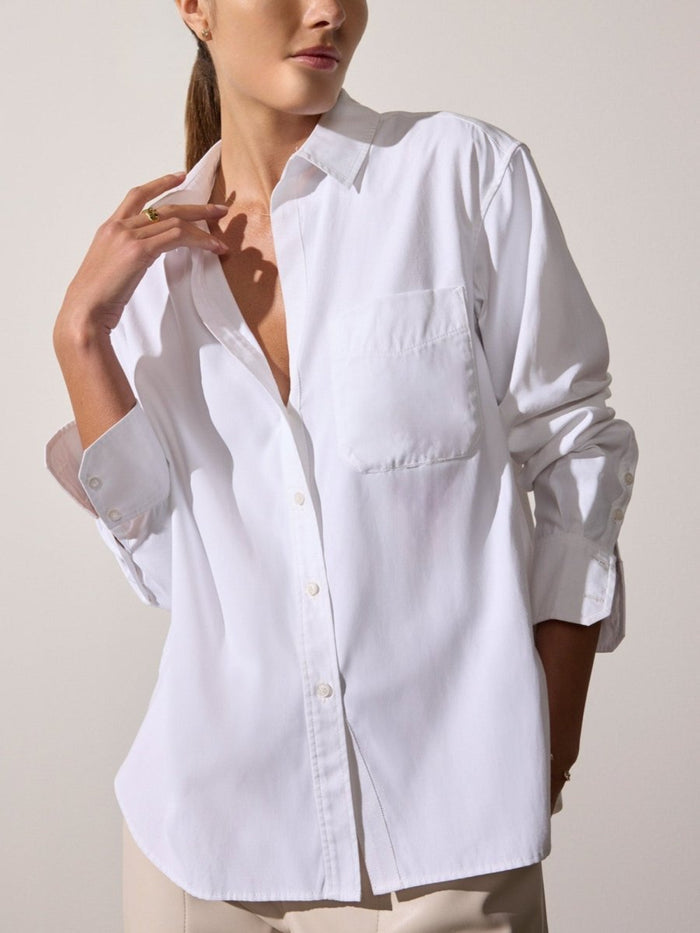 Model wearing a relaxed-fit white button-down shirt with chest pocket and long buttoned cuffs.