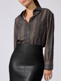 Woman wearing a charcoal striped button-down shirt with brown and gold vertical stripes, paired with a black faux-leather skirt.