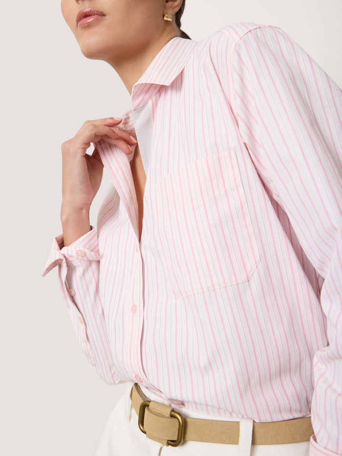 Woman wearing a pink and white striped button-down shirt with a belt