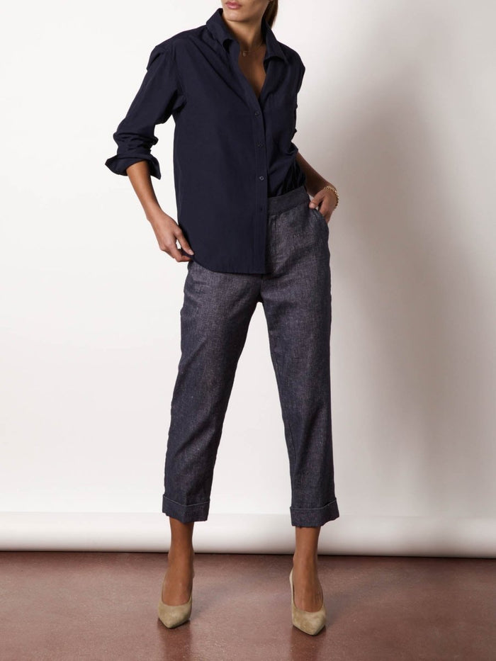 Navy button-down shirt styled with cropped denim trousers and tan suede heels.