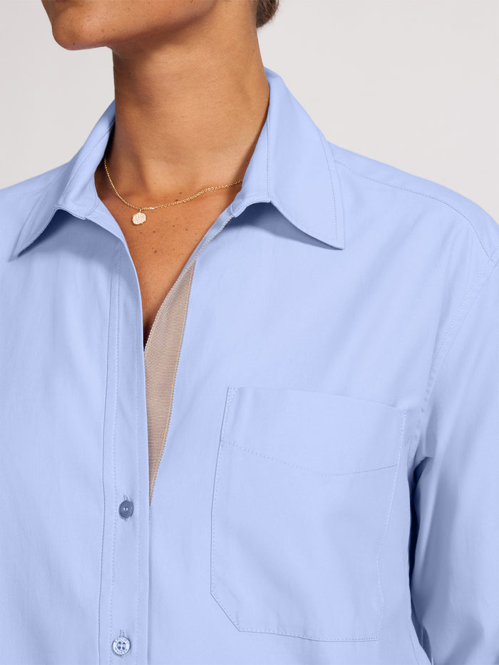 Close-up of the collar and chest pocket on a light blue button-front shirt
