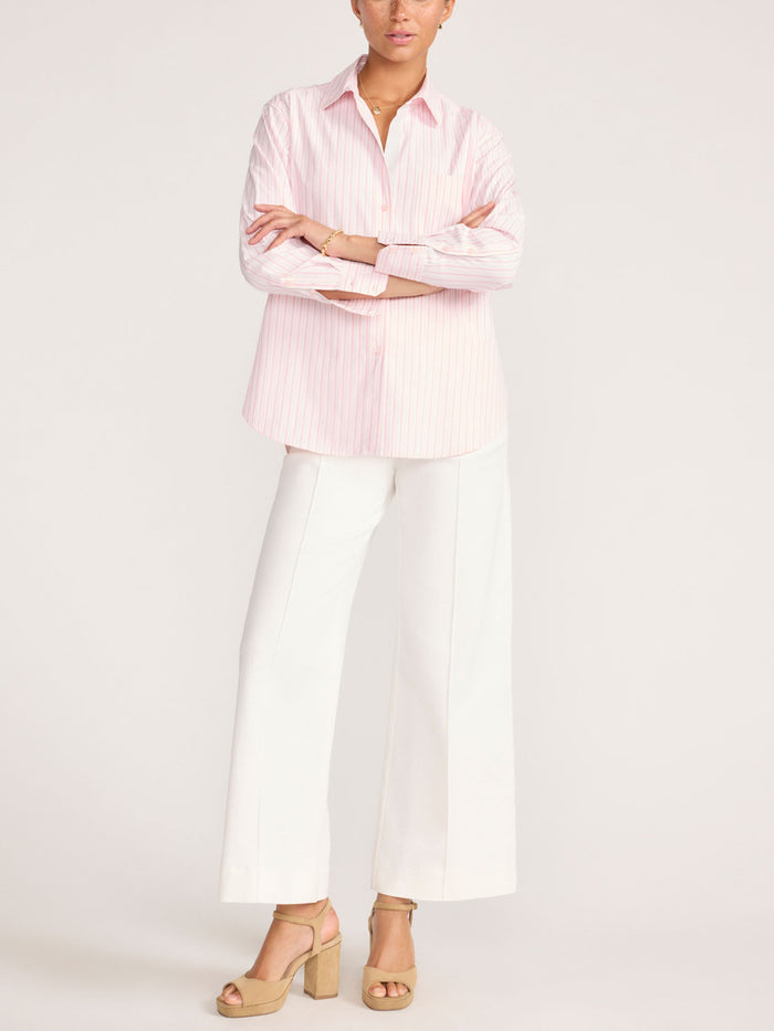 Full-length view of a woman wearing a pink and white striped shirt with white wide-leg trousers
