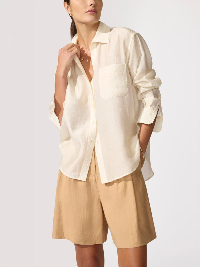 Woman wearing an oversized cream linen Everyday shirt with tan shorts