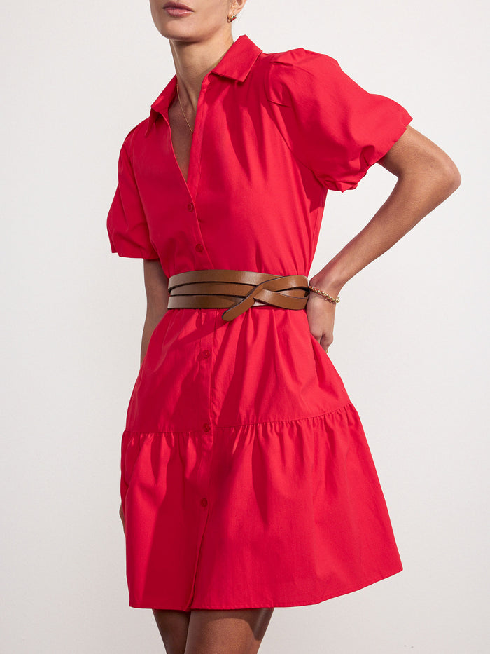 Woman wearing a red tiered mini shirtdress cinched at the waist with a woven leather belt