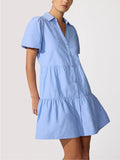 Woman wearing a periwinkle blue tiered ruffle mini shirtdress with puff sleeves and front pockets.