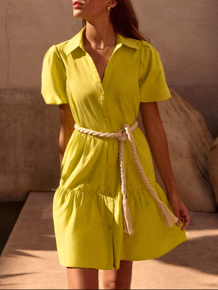 Close-up of a woman wearing a chartreuse yellow shirtdress with a rope tassel belt