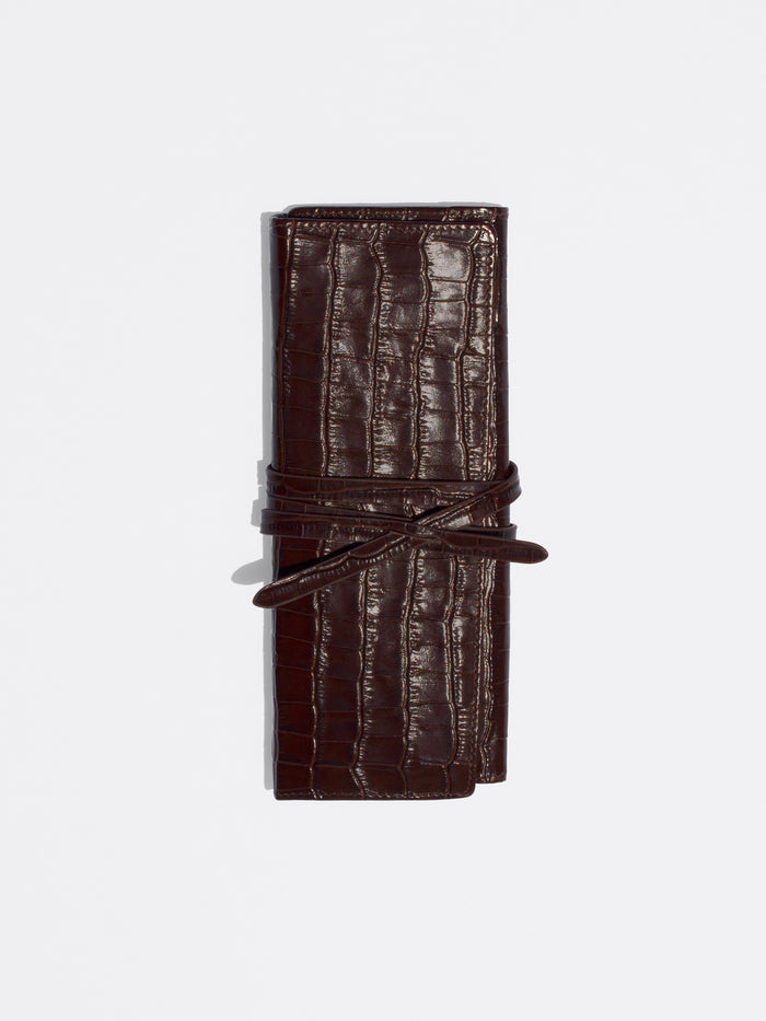 Dark brown crocodile-embossed leather roll-up case tied with a matching leather strap