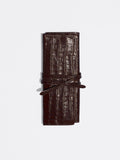 Dark brown crocodile-embossed leather roll-up case tied with a matching leather strap