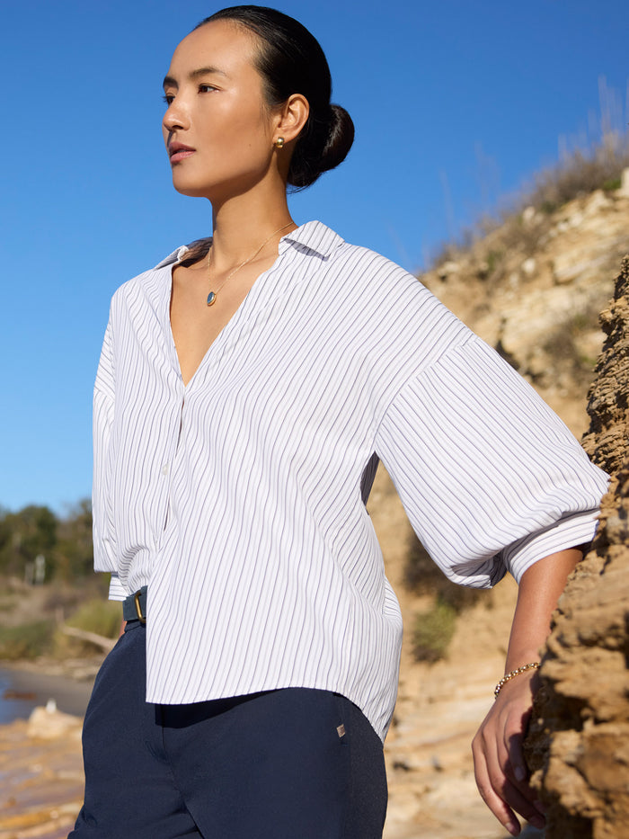 Woman wearing an oversized pinstripe collared shirt and navy pants outdoors