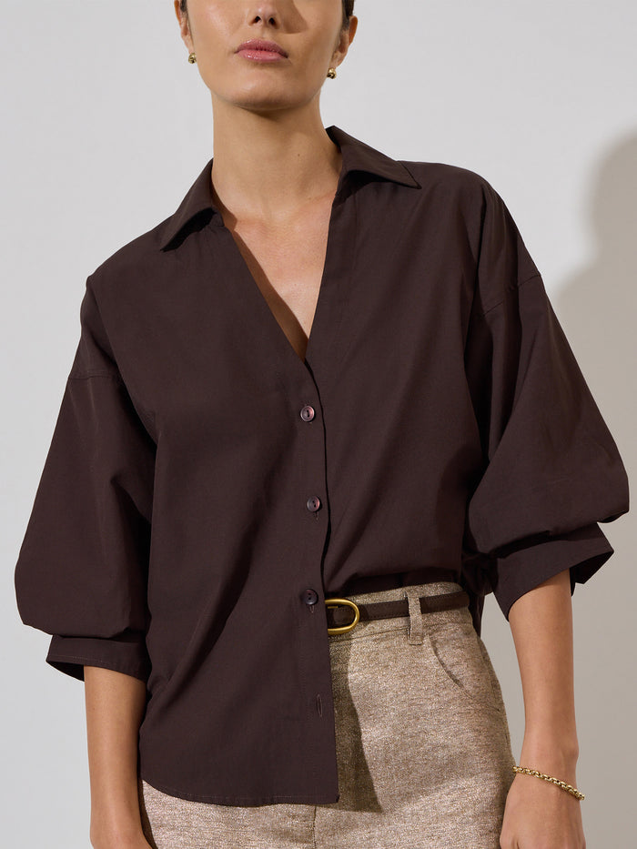 Kate shirt in java, an oversized dark brown button-up styled with a belt and metallic pants.