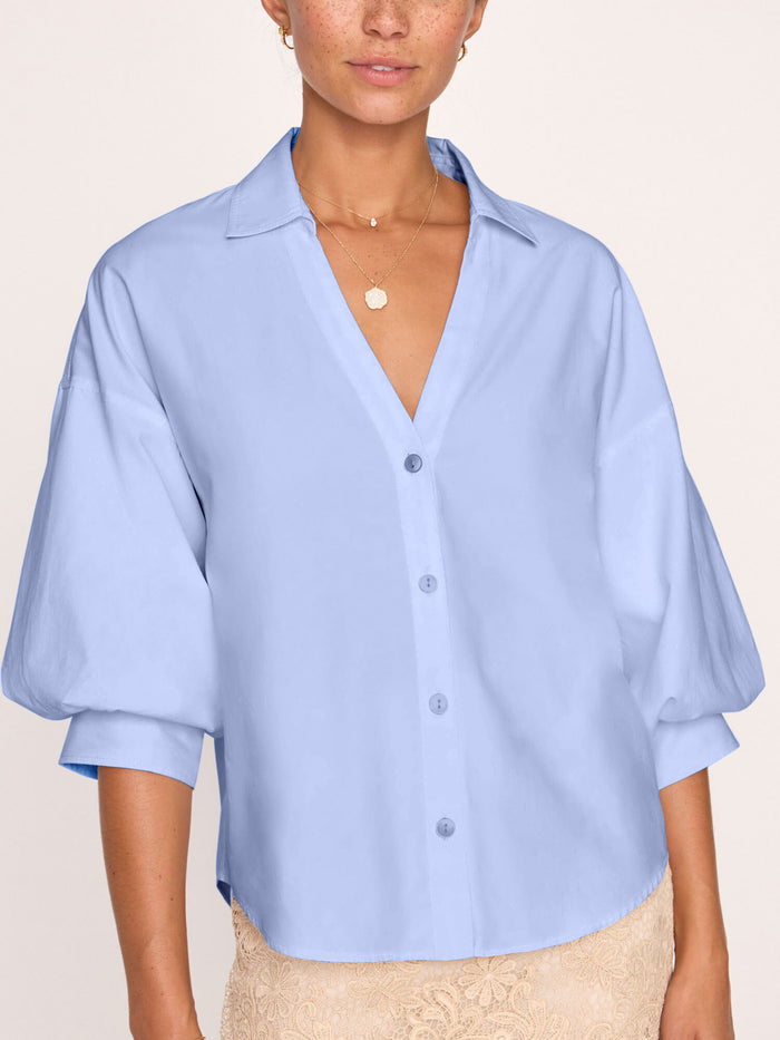 Front view of a light blue V-neck blouse, worn by a model