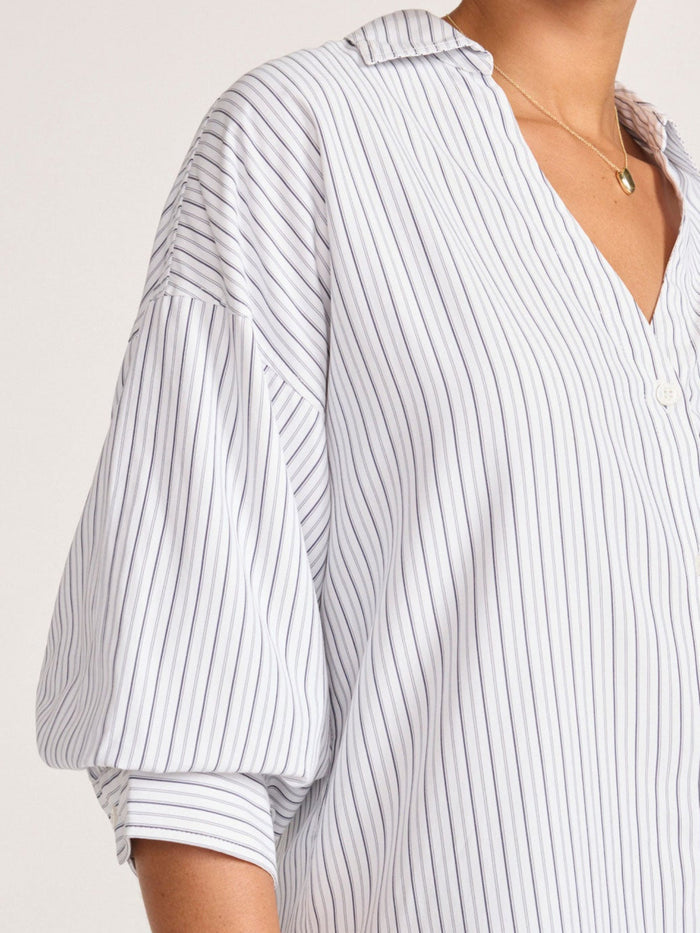 Close-up of an oversized navy striped shirt with a dramatic bishop sleeve and popover collar