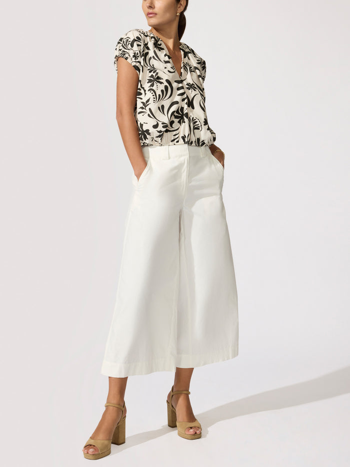 Full-length studio shot of the Louie Printed Top in a black-and-white Estara print styled with white wide-leg trousers