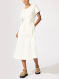 Woman wearing an ivory short-sleeve midi dress with a tie waist and tan platform sandals