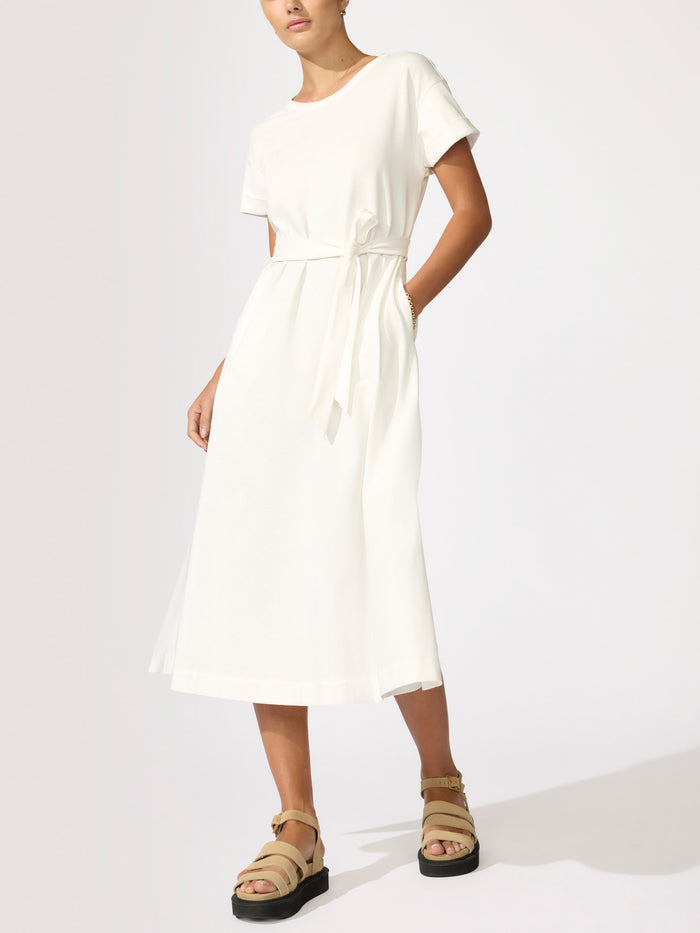 Woman wearing an ivory short-sleeve midi dress with a tie waist and tan platform sandals
