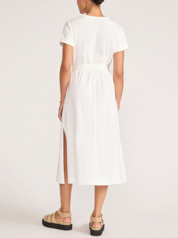 Back view of a model in the ivory Marah t-shirt midi dress with a belted waist and back slit.