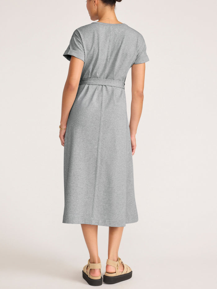 Back view of a woman wearing a grey heathered T-shirt dress with a tie waist and platform sandals