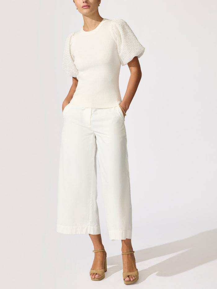 Woman wearing a white textured puff-sleeve knit top with cropped wide-leg trousers and tan sandals
