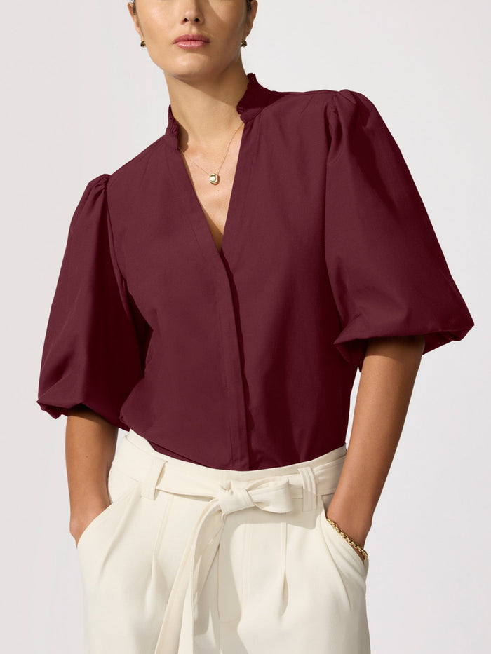 Woman wearing a burgundy puff-sleeve blouse with cream wide-leg trousers