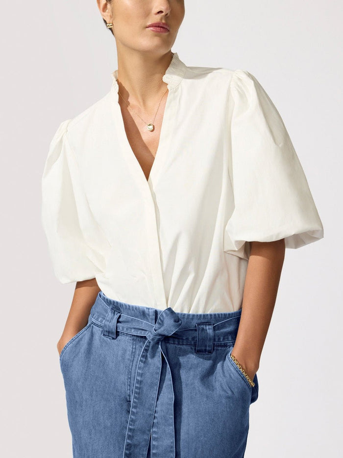 Woman wearing the Marla Shirt in Salt White, a white puff-sleeve blouse with a stand collar, styled with a denim skirt
