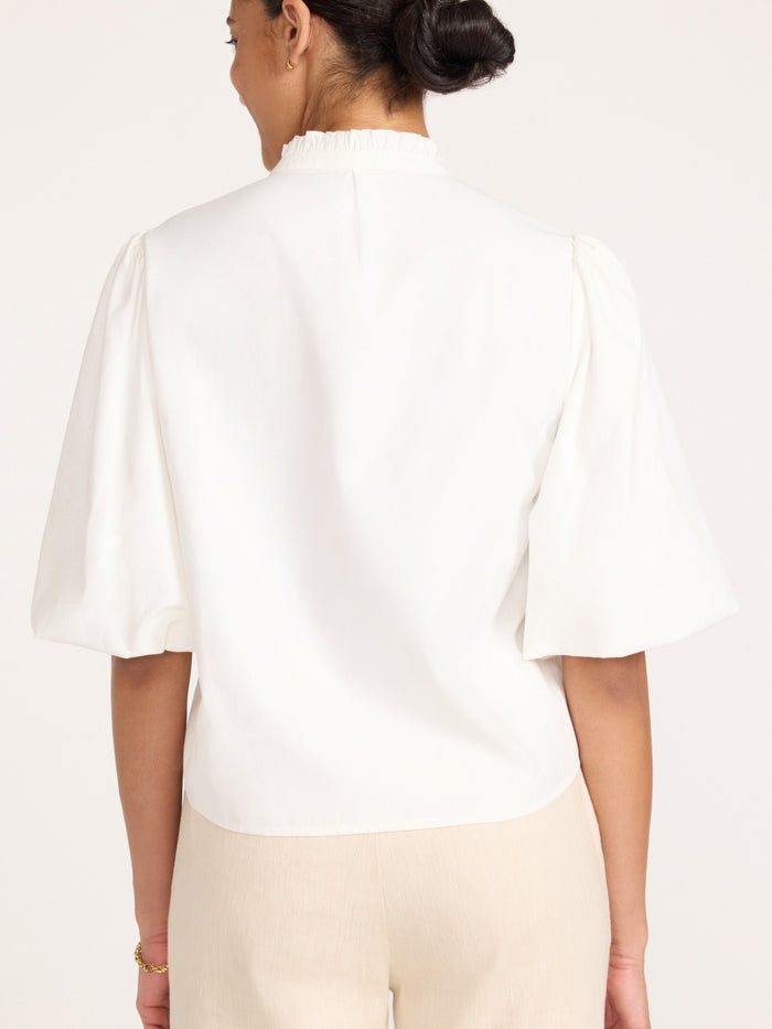 Back view of the Marla Shirt in Salt White with puff sleeves, styled with beige trousers