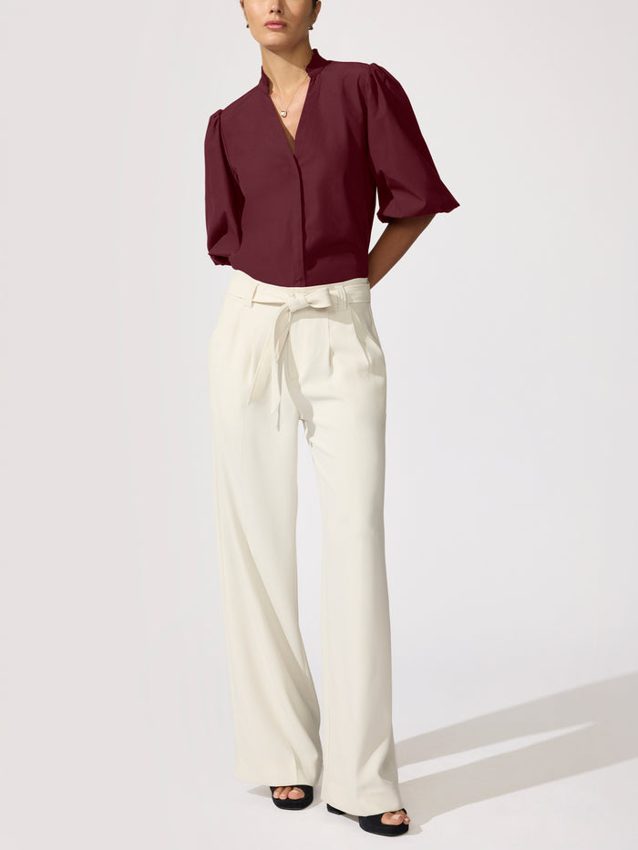 Woman wearing a burgundy puff-sleeve blouse with cream wide-leg trousers