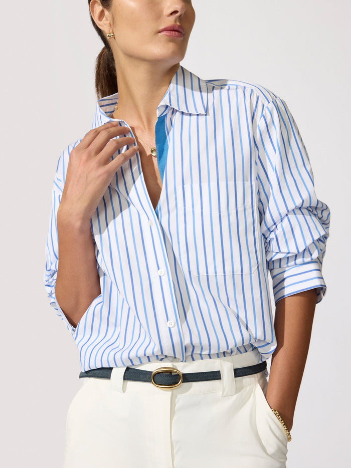 Close-up of a woman wearing a blue and white striped shirt with rolled-up sleeves