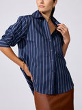 Pia shirt in Hartford stripe navy, model wearing button-up shirt styled with a brown leather skirt