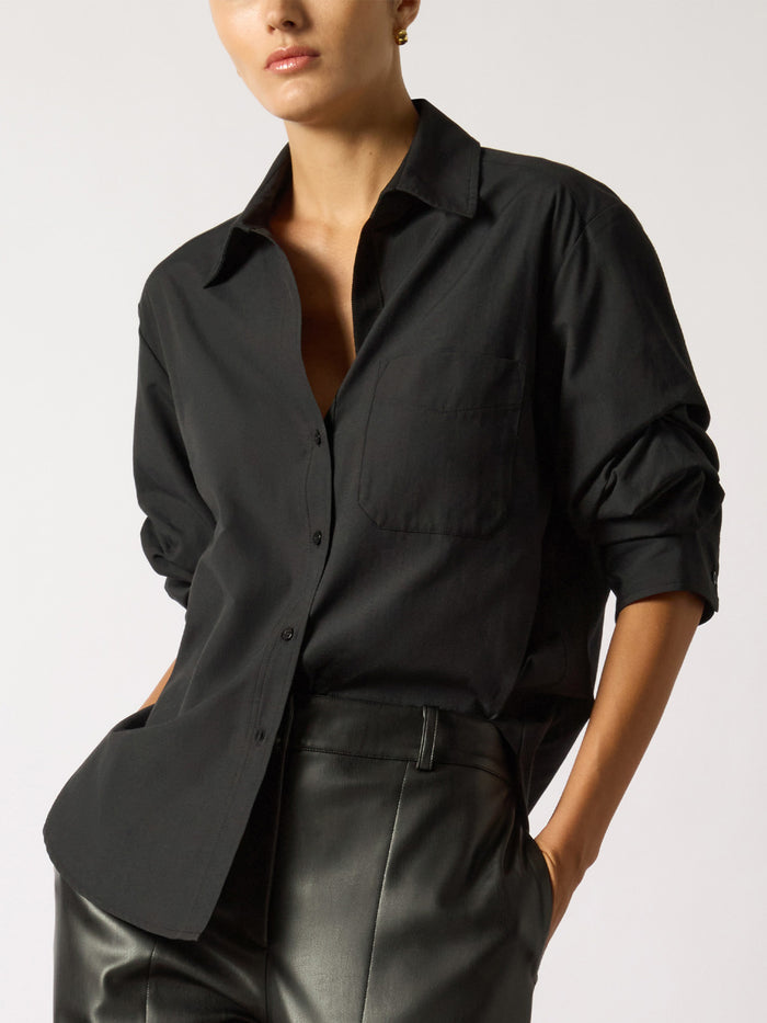Woman wearing an oversized black button-up shirt with black faux-leather pants