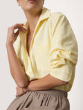 Woman wearing a pale yellow blouse with rolled sleeves and a taupe skirt